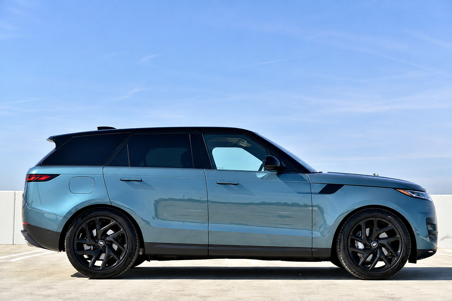 Side profile of the light blue Range Rover Sport, black roof and black wheels against a clear sky