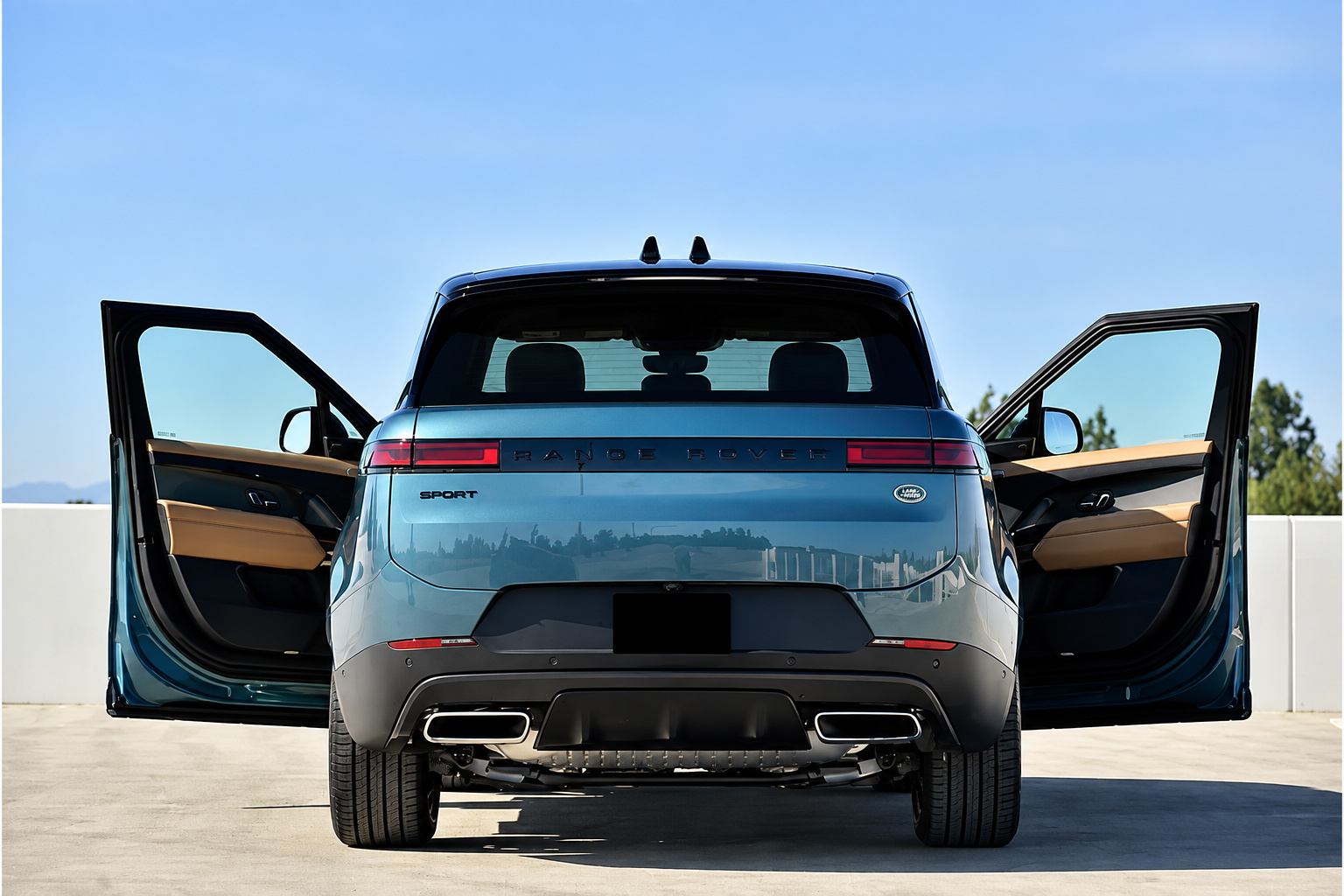 Rear view of the light blue Range Rover Sport with both front doors open and the quad exhaust tips