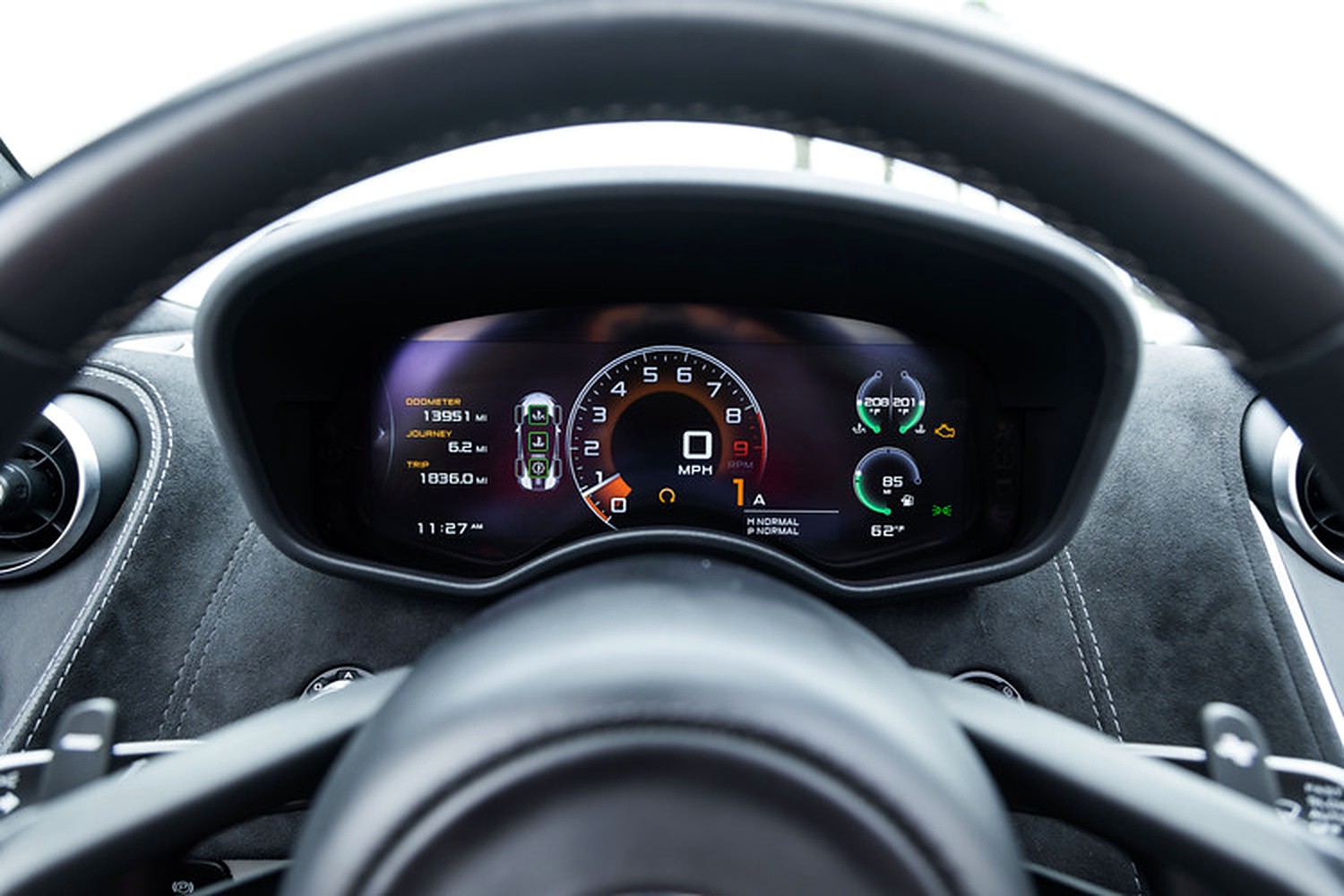 Digital instrument cluster of the McLaren 570S Spider seen through the steering wheel
