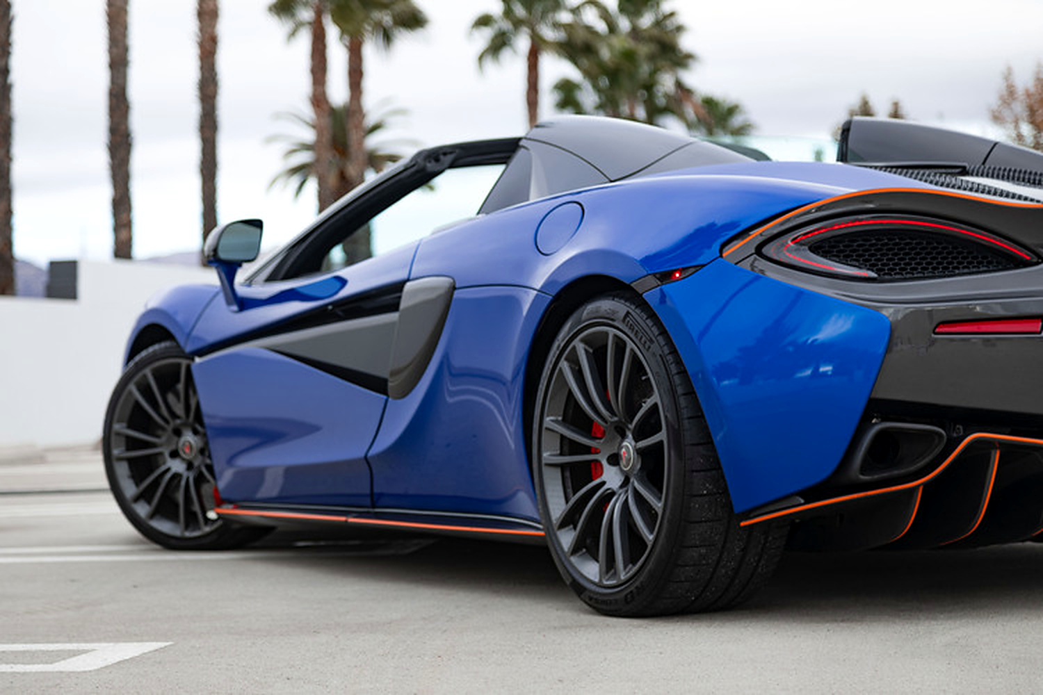 Rear three-quarter of the 570S Spider with the hardtop down and doors closed, buttresses behind the seats