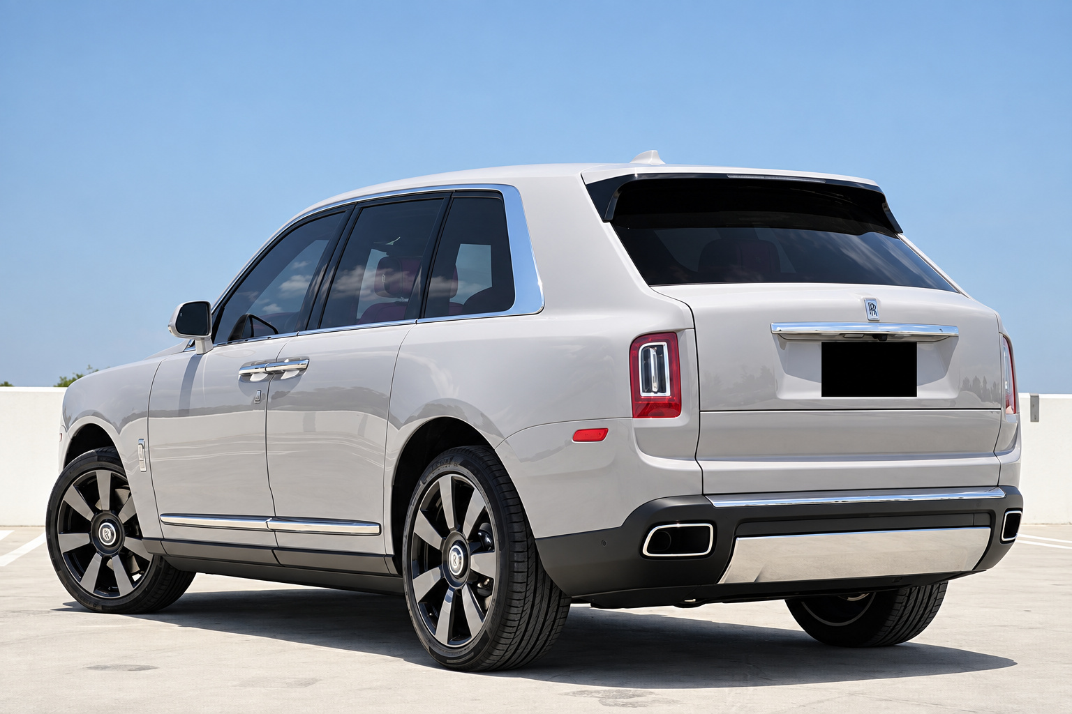 Rear three-quarter view of the white Rolls Royce Cullinan showing the split tailgate and chrome trim