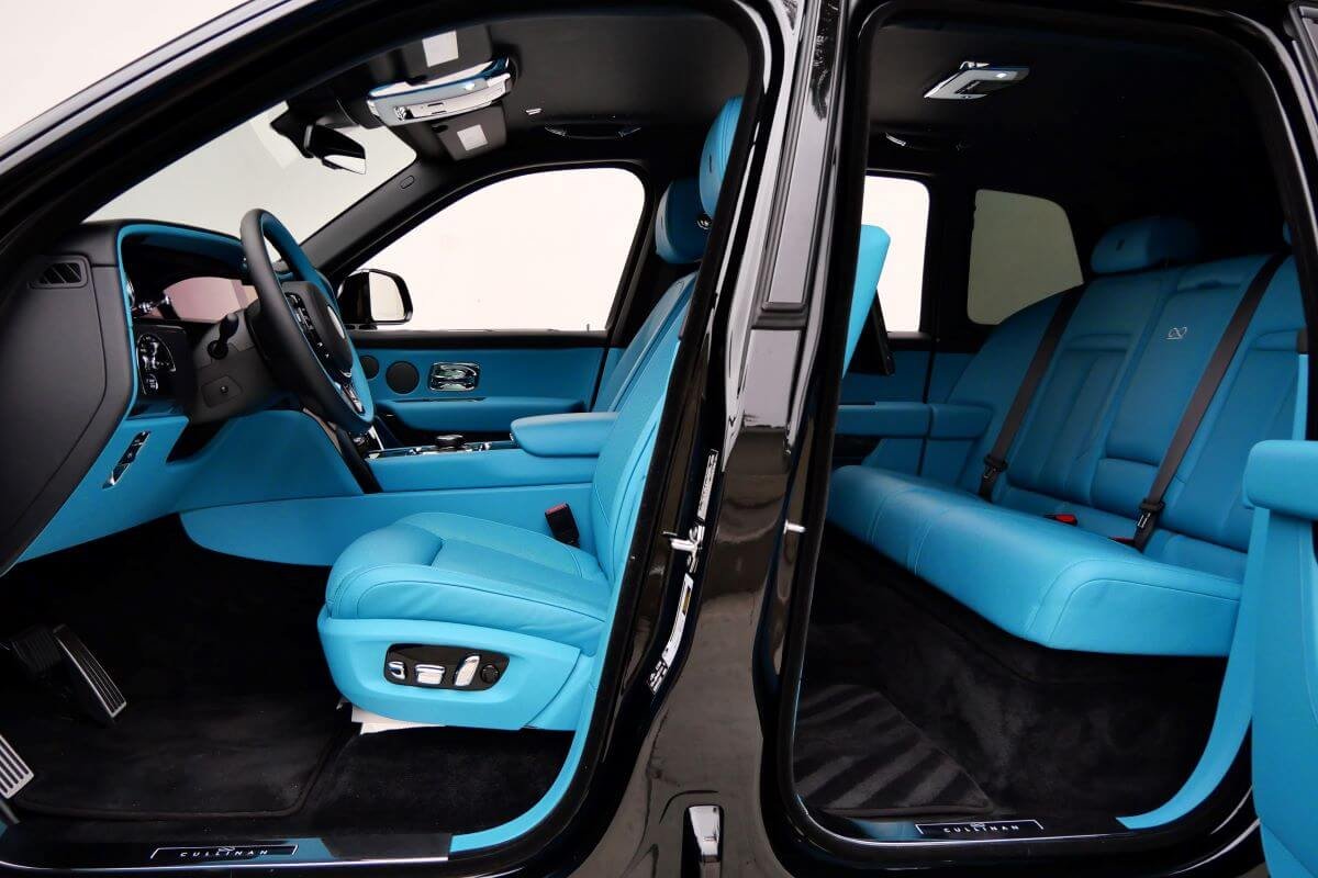 Open rear door of the Black Badge Cullinan showing turquoise front and rear seats and black lambswool mats