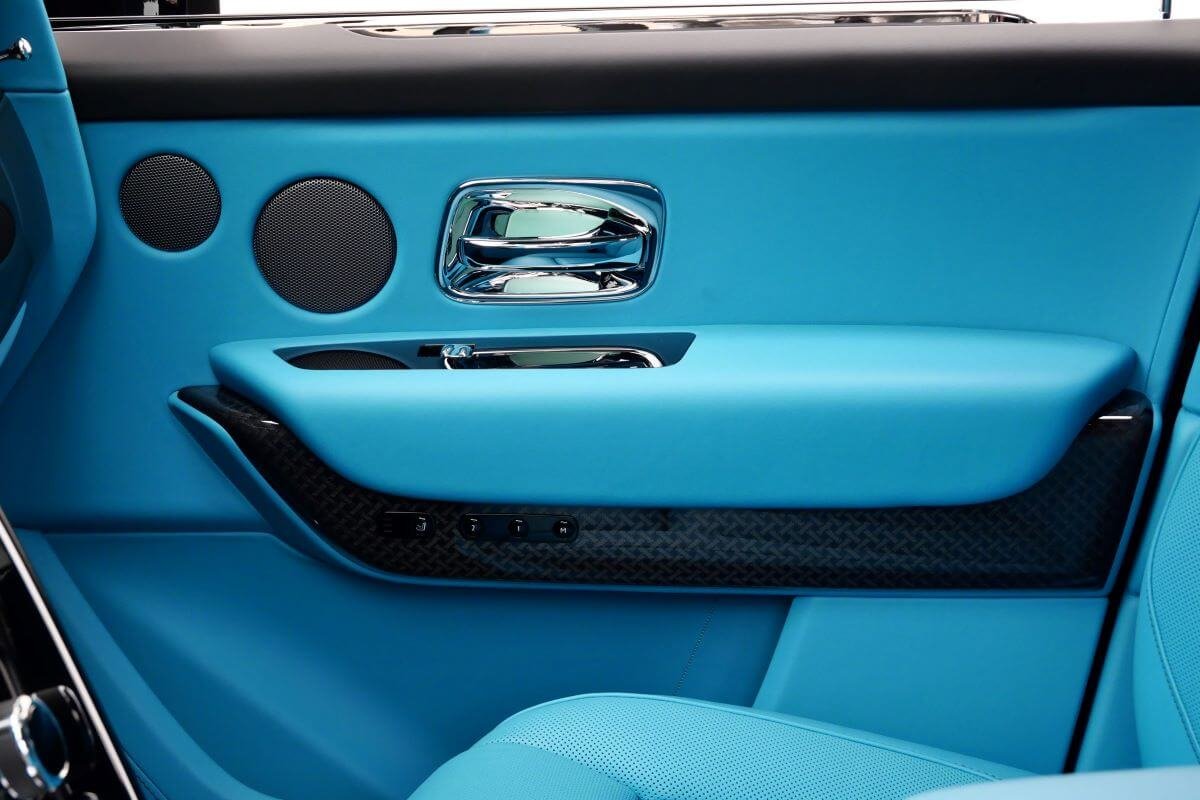 Rear door panel in turquoise leather with chrome handle and black speaker grilles in the Black Badge Cullinan