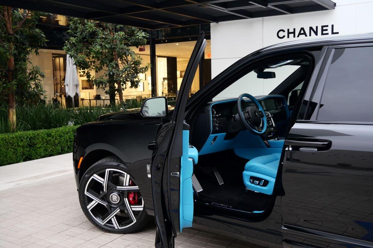 Black Cullinan Black Badge Series II with the rear coach door open outside a Beverly Hills storefront