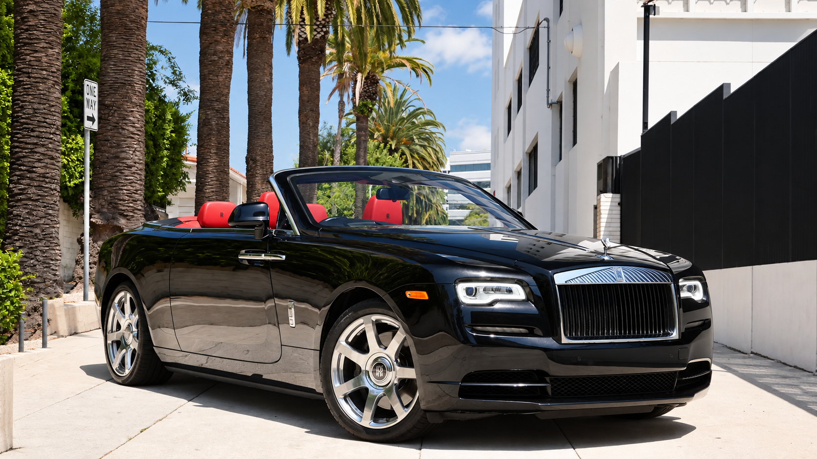 Black Rolls Royce Dawn with the roof down and red leather seats on a palm-lined street in Los Angeles