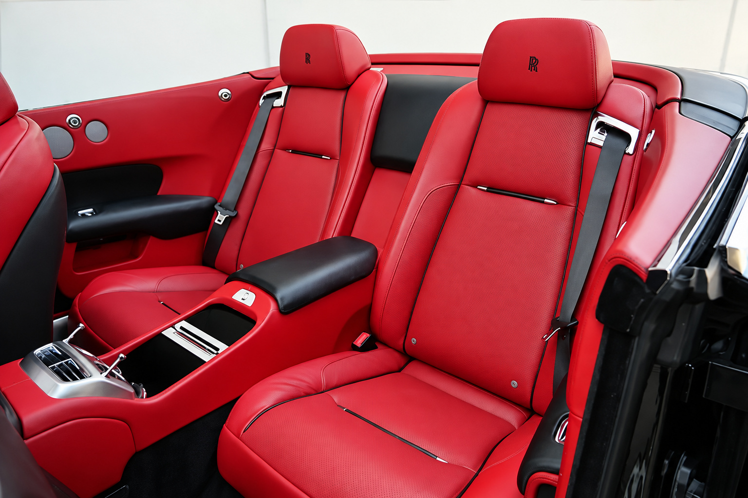 Rear seats of the Rolls Royce Dawn in red leather with the center armrest down and the roof stowed