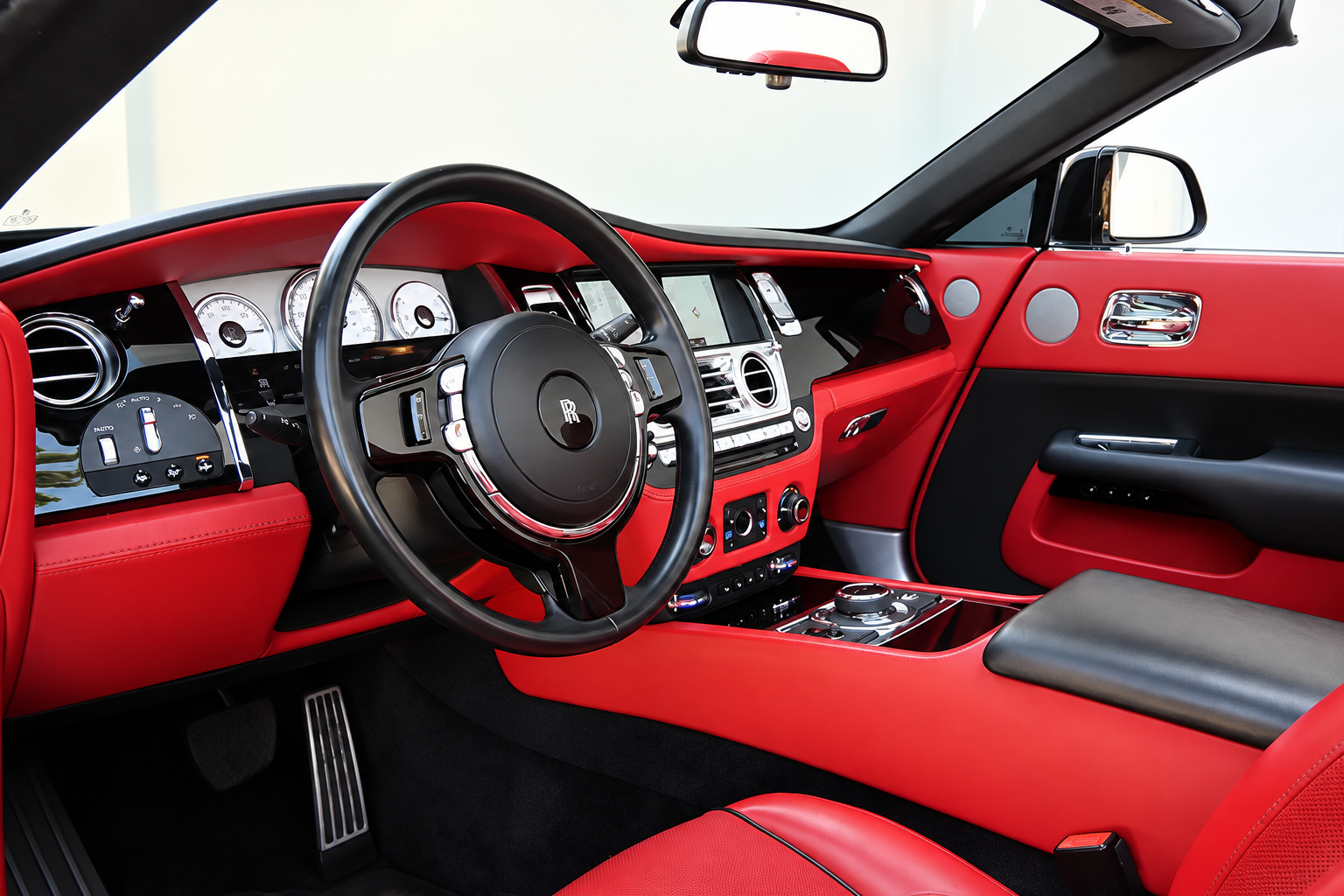 Driver's view of the Dawn steering wheel, chrome-ringed gauges and red leather door panel