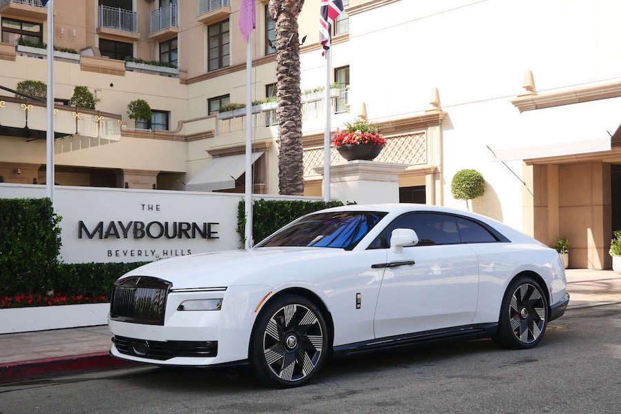 Side profile of the white Rolls Royce Spectre on black wheels outside The Maybourne Beverly Hills