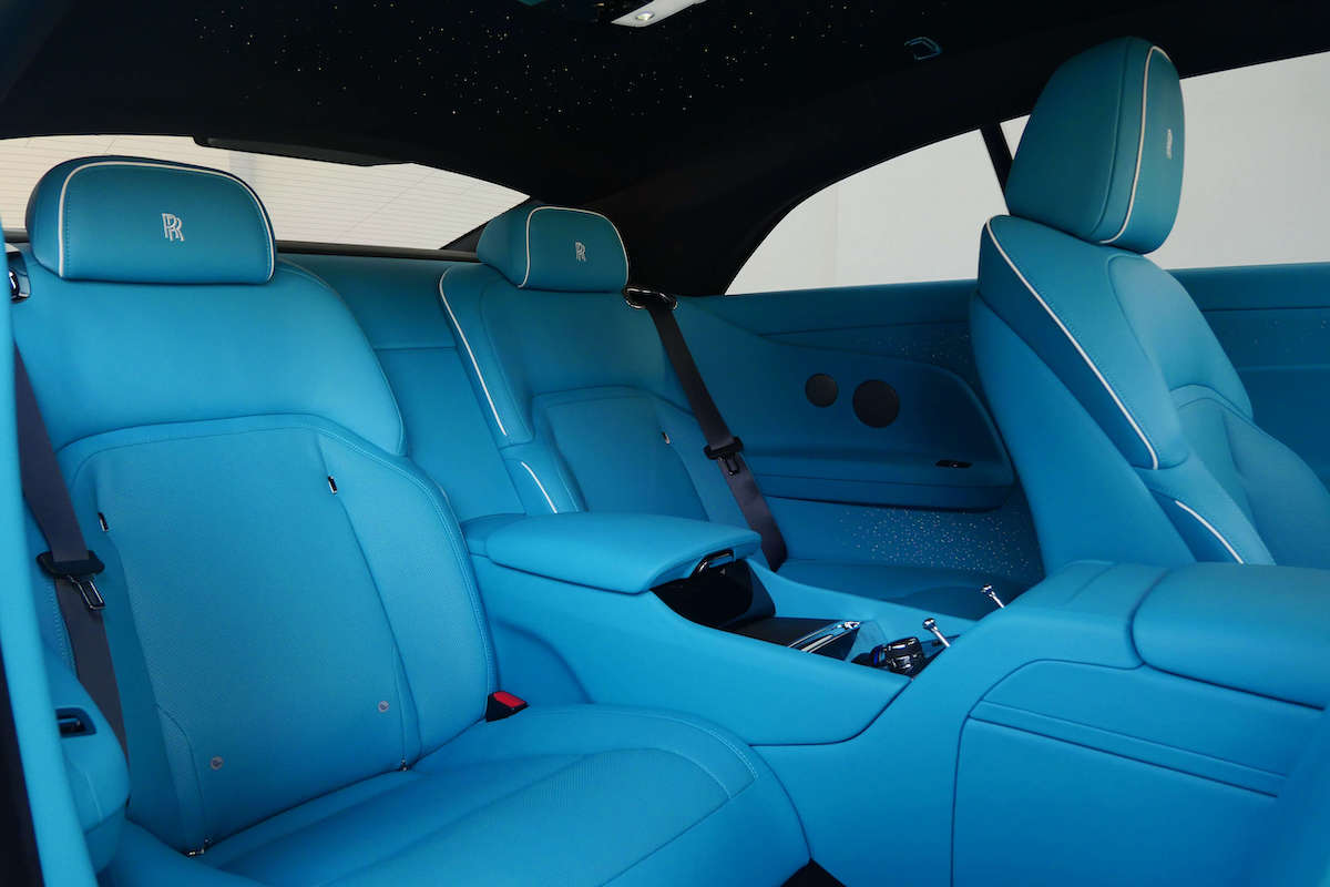 Turquoise rear seats of the white Spectre with the center console and white piping under the starlight roof