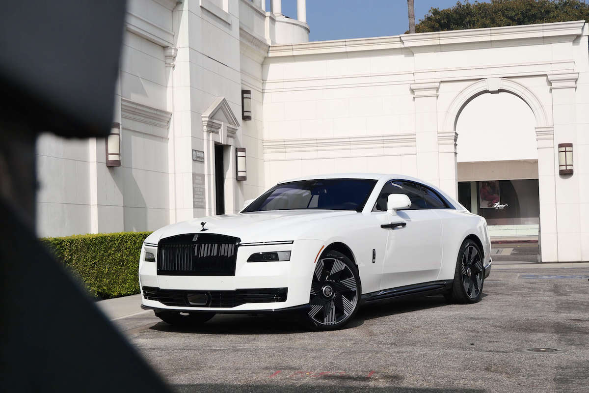White Rolls Royce Spectre with black grille and wheels parked beside a white building in Beverly Hills