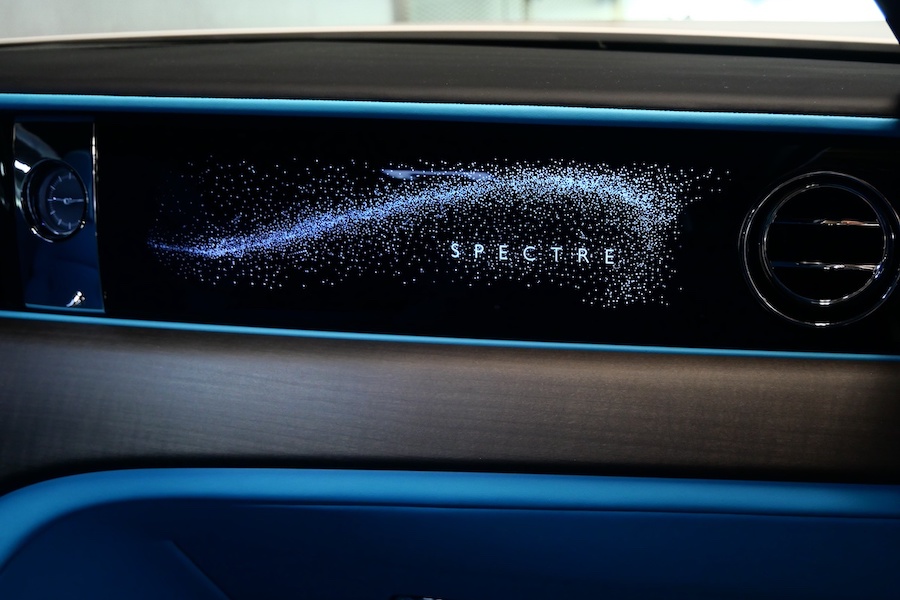 Illuminated Spectre nameplate glowing across the passenger side of the dash with turquoise trim below