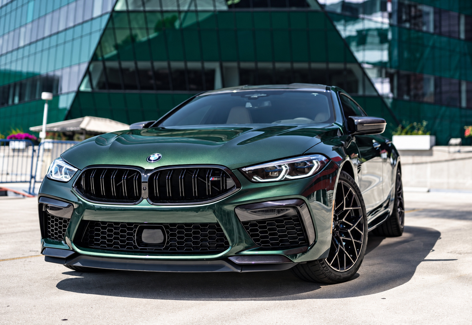 Close front three-quarter of the green M8 Competition Gran Coupe, black kidney grille and black wheels