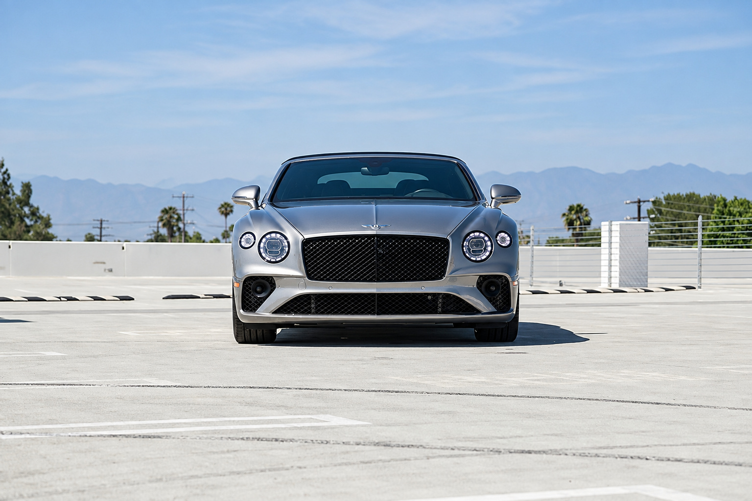 Head-on view of the silver Bentley GTC First Edition with the roof down and a mountain ridge behind