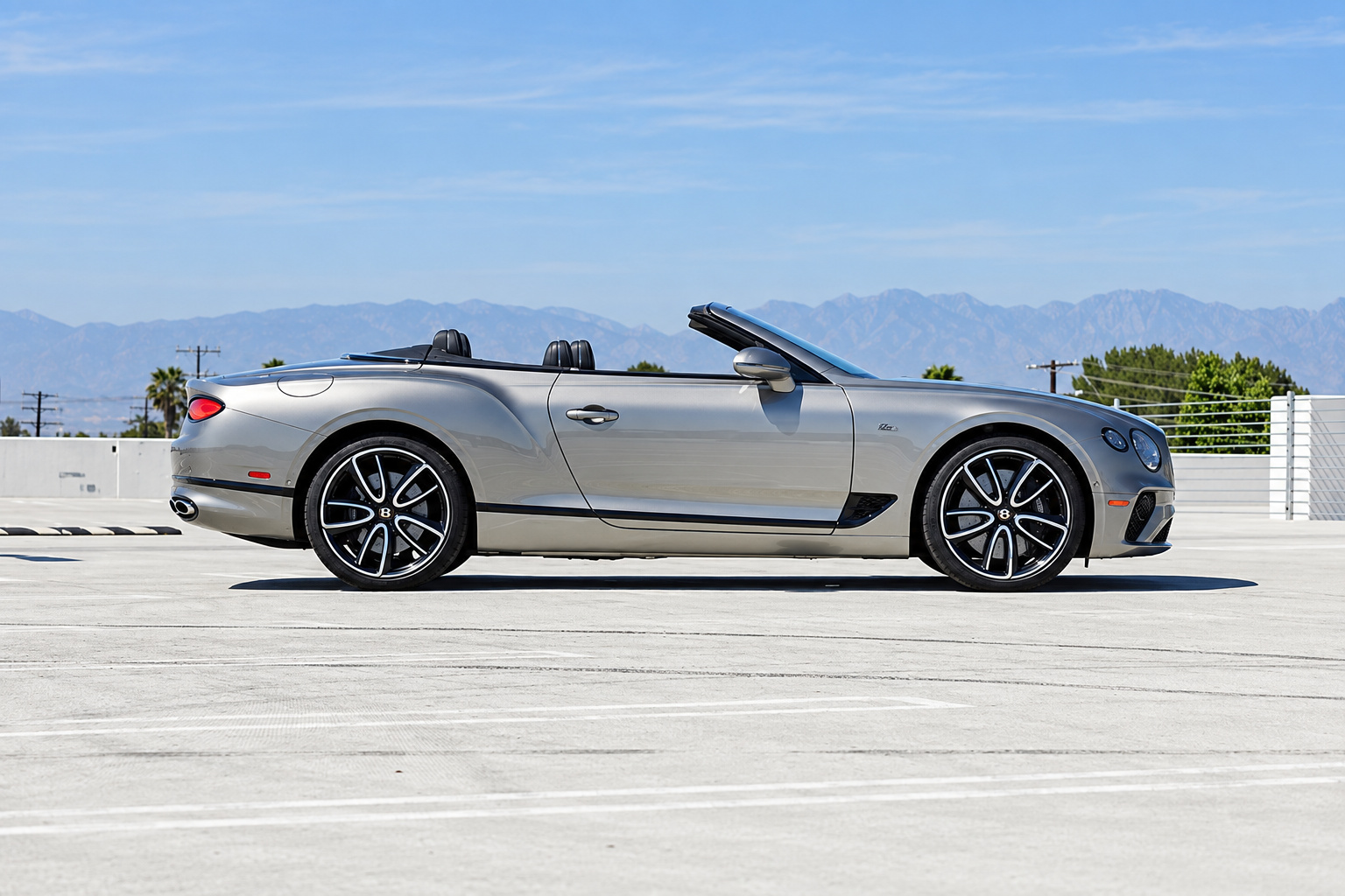 Side profile of the silver Continental GTC roof down, dark multi-spoke wheels, ivory headrests above the door line