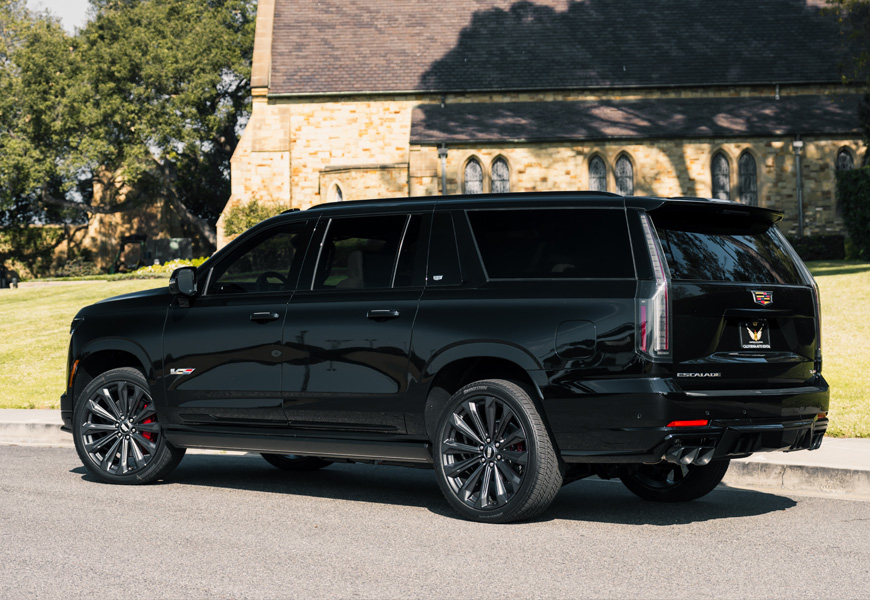 Rear three-quarter of the long-body black Escalade-V, quad exhaust tips, black 24 inch wheels and red calipers
