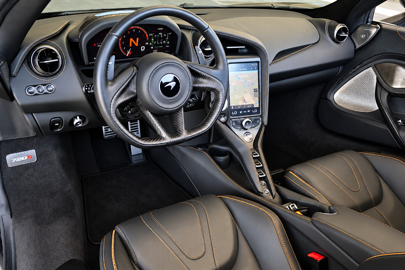 Driver's view in the McLaren 720S Spider, steering wheel, driver display and IRIS portrait screen with orange stitching