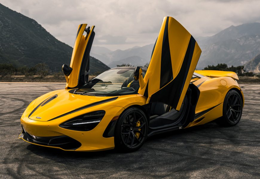 Yellow McLaren 720S Spider MSO with black stripes, dihedral doors up and roof down at a turnout on Angeles Crest Highway