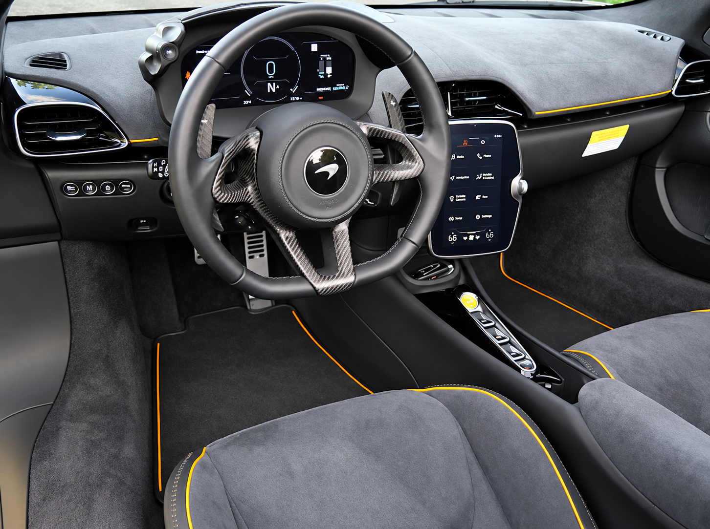 Steering wheel and dash of the McLaren Artura Spider, black Alcantara with orange piping and the portrait touchscreen