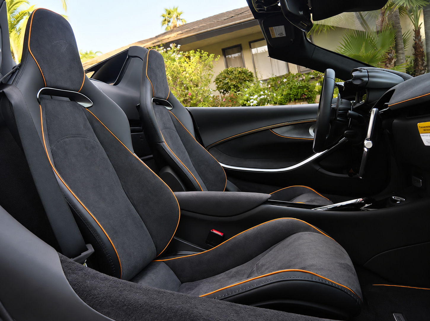 Black Alcantara seats with orange contrast stitching in the Artura Spider, shot from the open door with the roof down