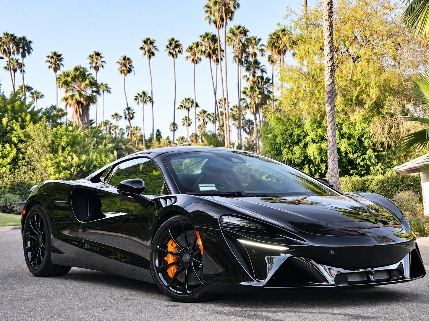 Front three-quarter of the black McLaren Artura Spider, roof down, orange brake caliper showing through the front wheel