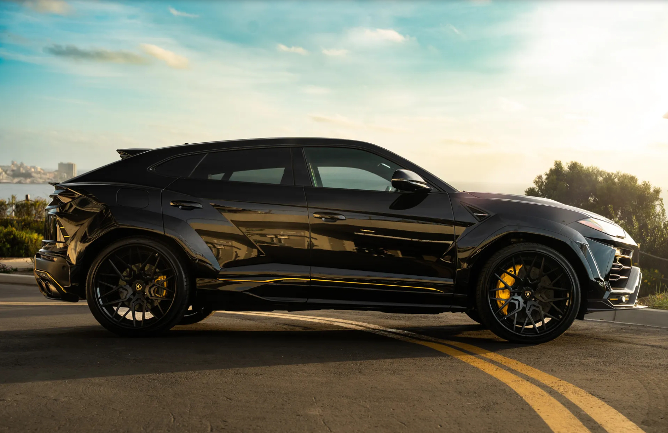 Side profile of the black Urus Widebody on the San Diego coast, flared arches, black wheels and yellow calipers