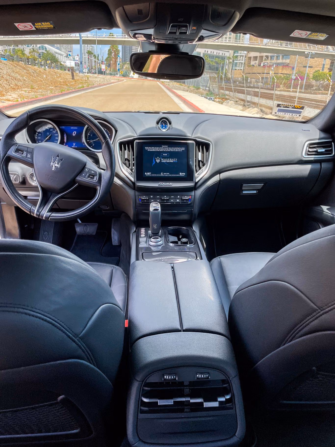 Black leather Maserati Ghibli cabin seen from the back seat, dash, touchscreen and centre console