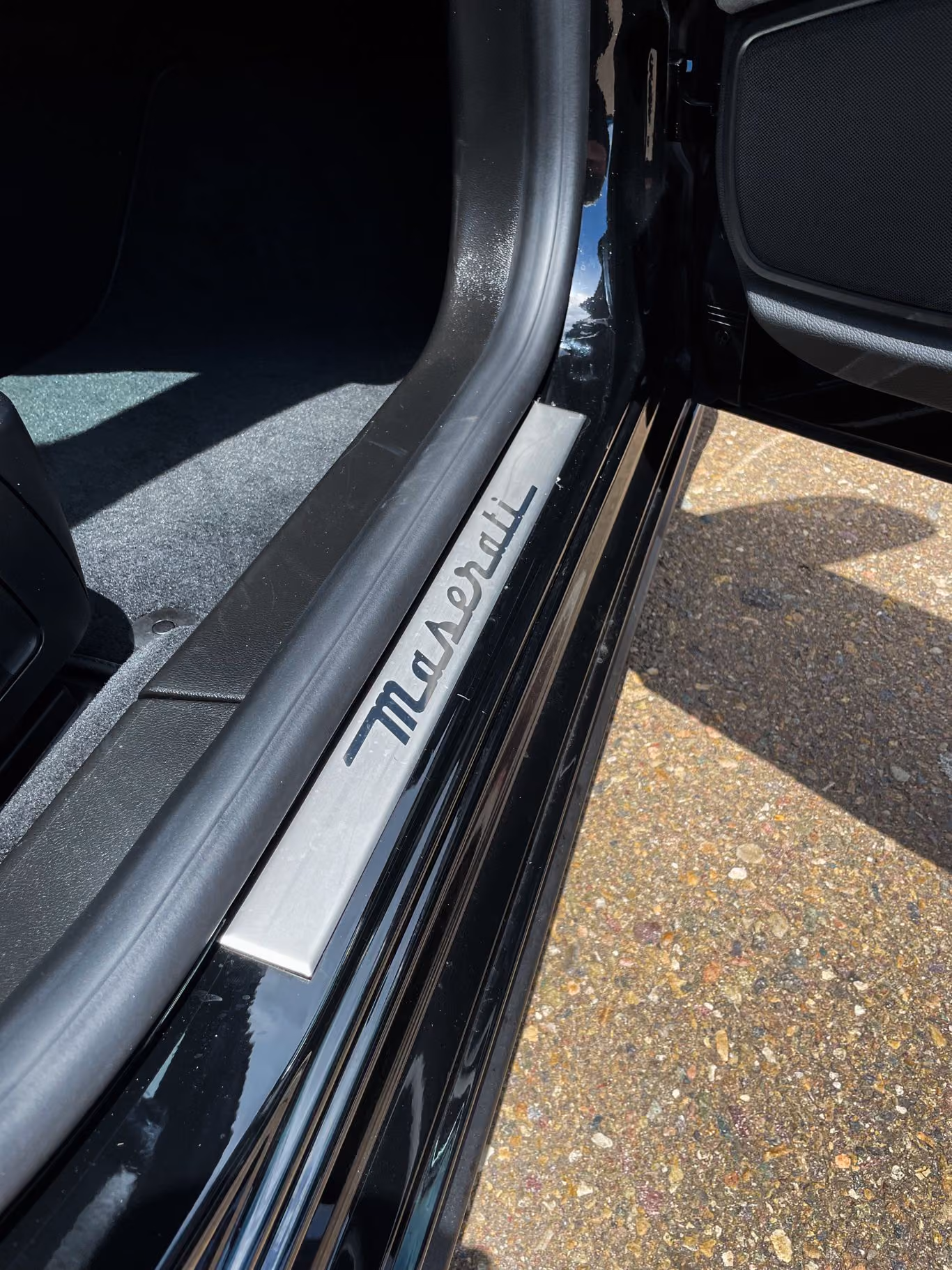 Maserati script on the aluminum door sill plate of the black Ghibli, driver's door open