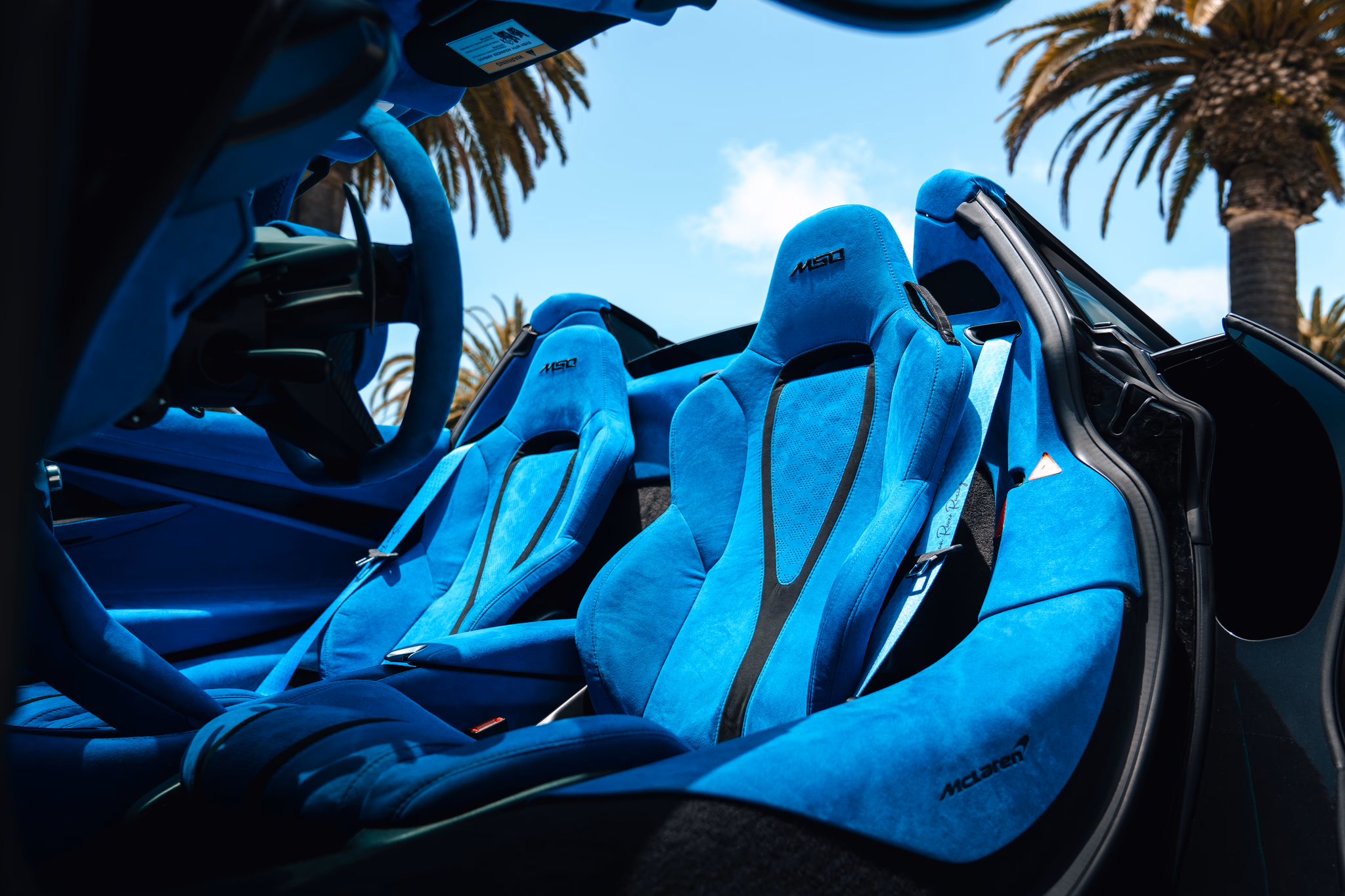 Blue alcantara cabin of the satin black McLaren 720S Spider seen through the open passenger door