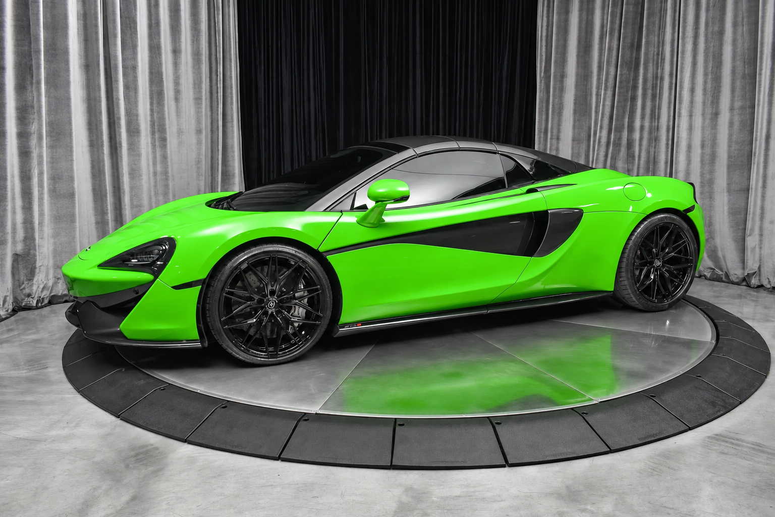 Front three-quarter of the Mantis Green McLaren 570S Spider, doors closed, roof down, under studio lights
