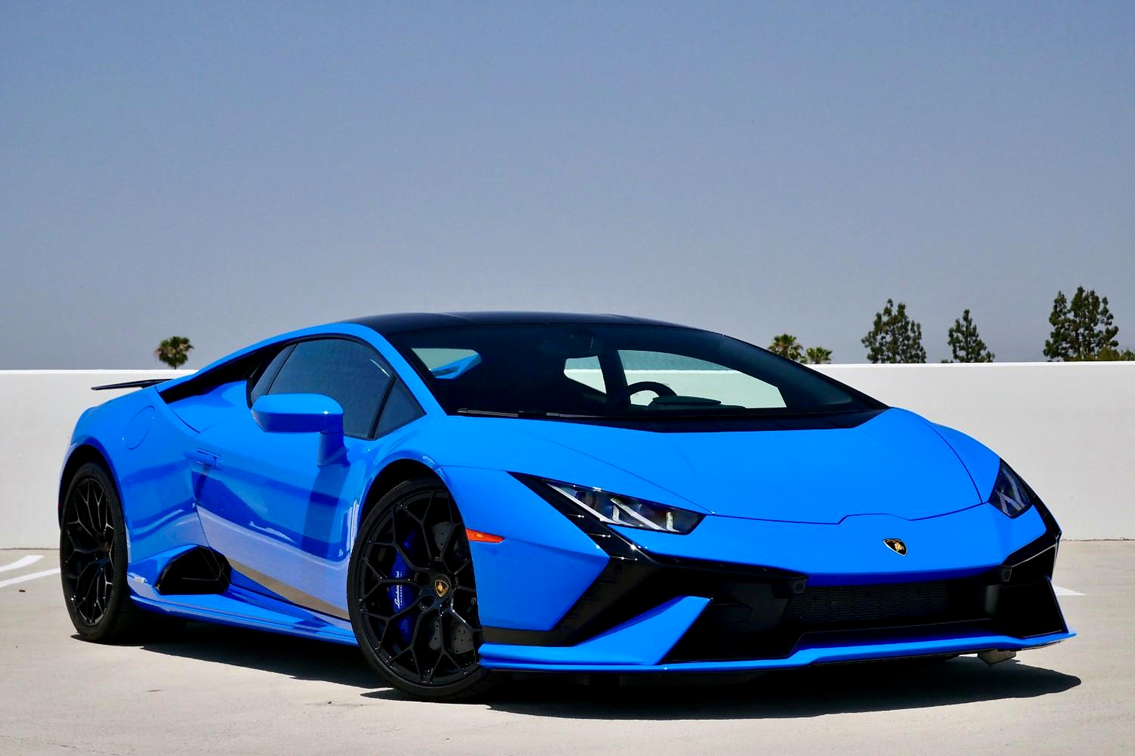 Blu Le Mans Lamborghini Huracan Tecnica, front three-quarter on a rooftop deck with black wheels and blue calipers