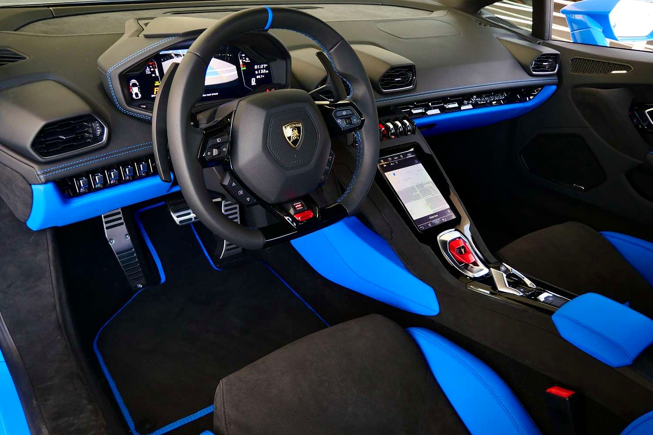 Driver's view of the Tecnica cabin, flat-bottom wheel, red start flap and the blue center console