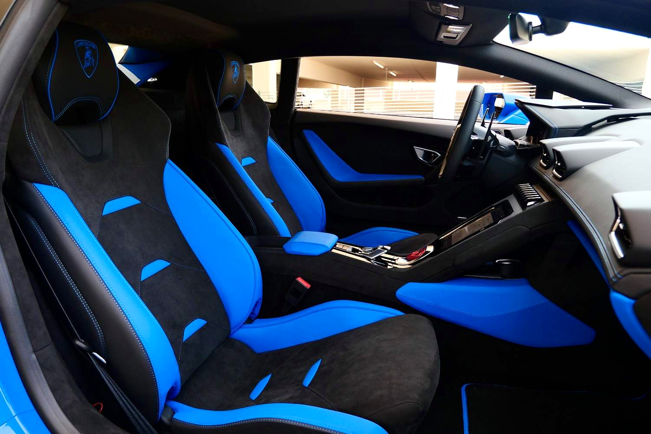 Both seats of the blue Huracan Tecnica seen from the open driver's door, black alcantara and blue inserts