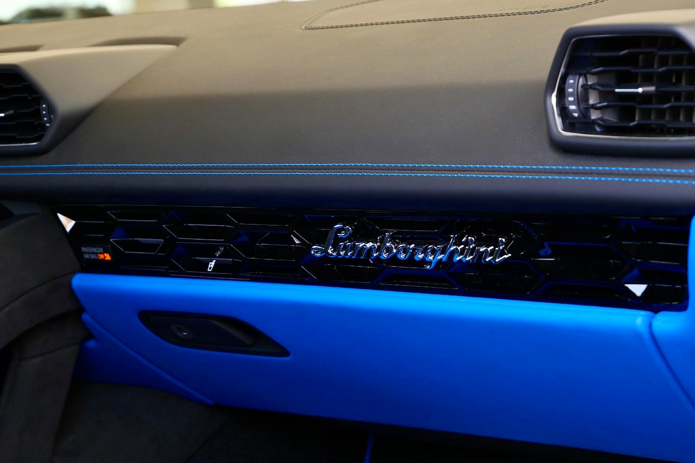 Lamborghini script on the passenger side dash of the Tecnica with blue stitching and a hexagonal vent