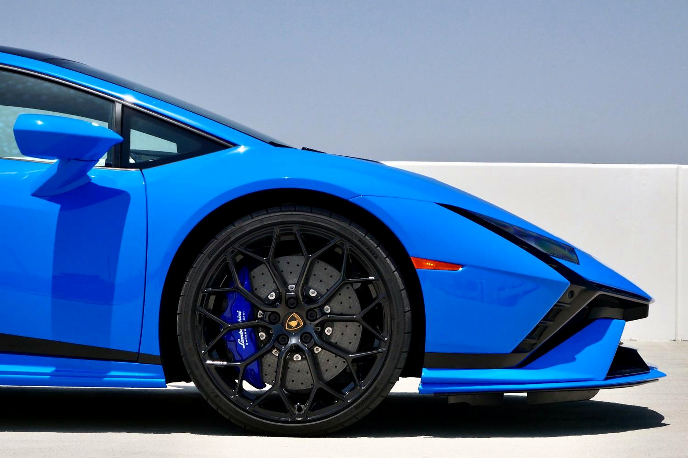 Close view of the Huracan Tecnica's black front wheel, blue brake caliper and Blu Le Mans fender