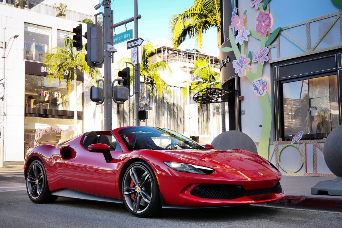 Red Ferrari 296 GTS with the roof down parked on Rodeo Drive in Beverly Hills, front three-quarter view