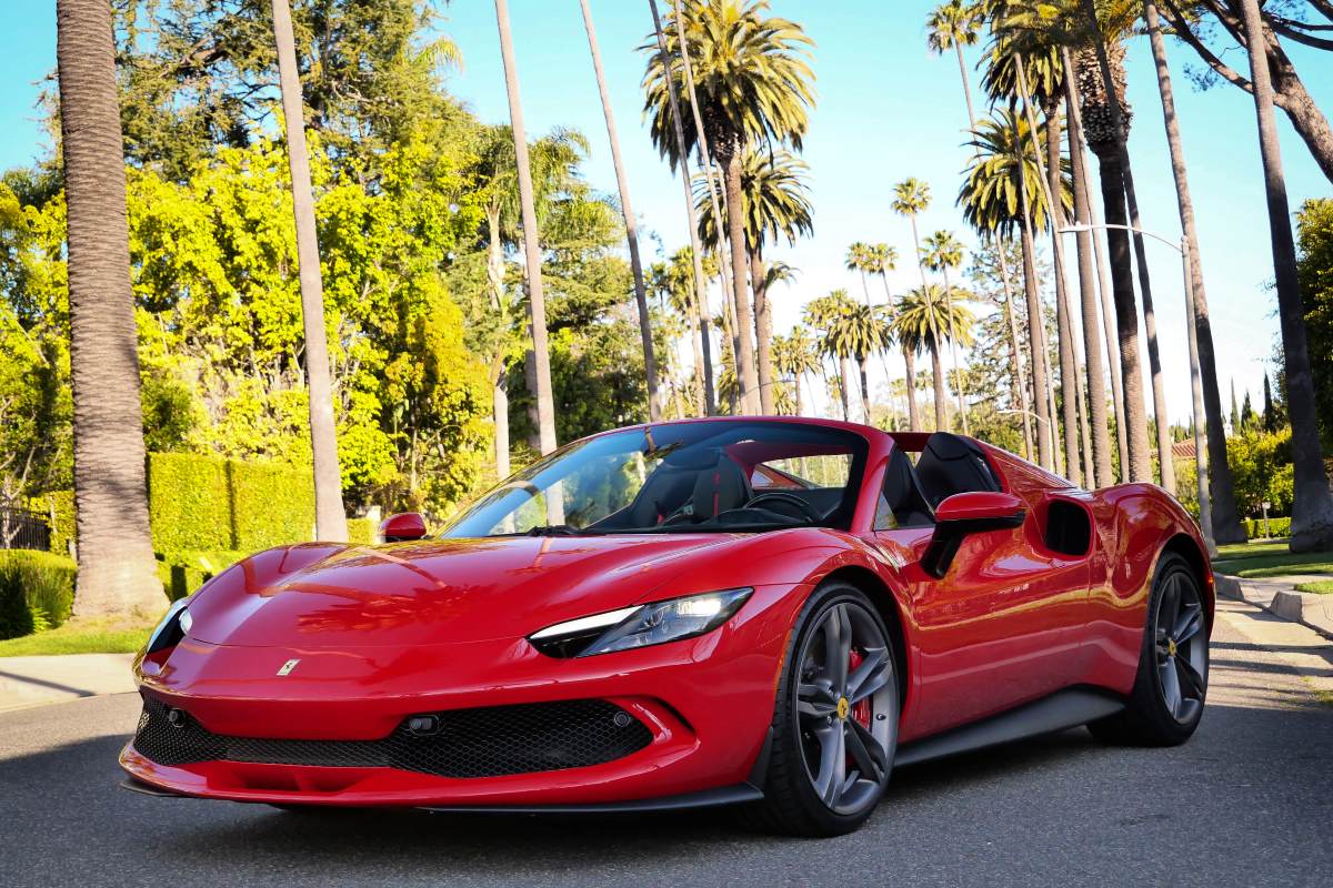Front three-quarter of the red Ferrari 296 GTS on a palm-lined Beverly Hills street, roof down