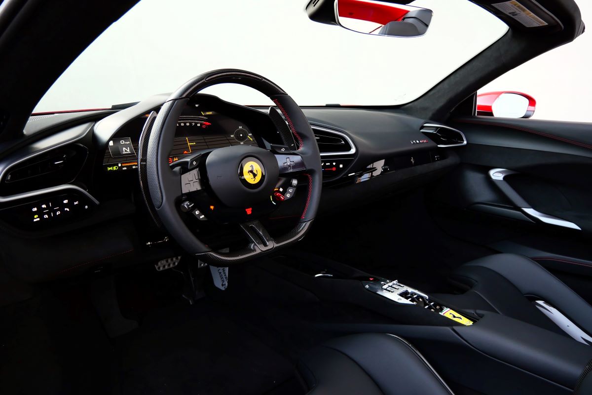 Driver's seat view across the 296 GTS cabin, carbon steering wheel and the digital cluster, roof open