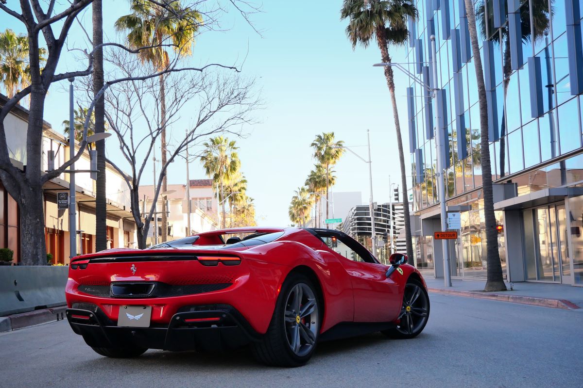 Rear three-quarter of the red 296 GTS parked below a glass office building in Beverly Hills, roof stowed