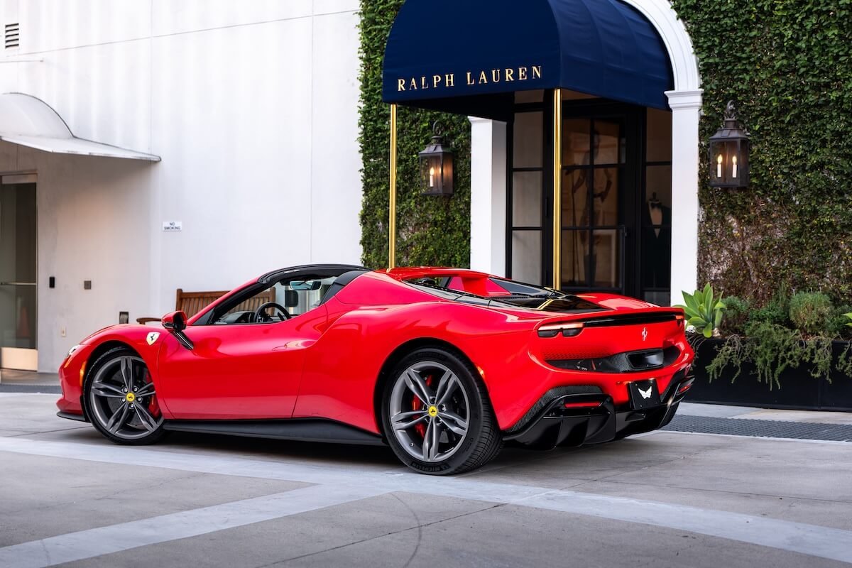 Rear view of the red Ferrari 296 GTS parked outside a Rodeo Drive storefront with a navy awning