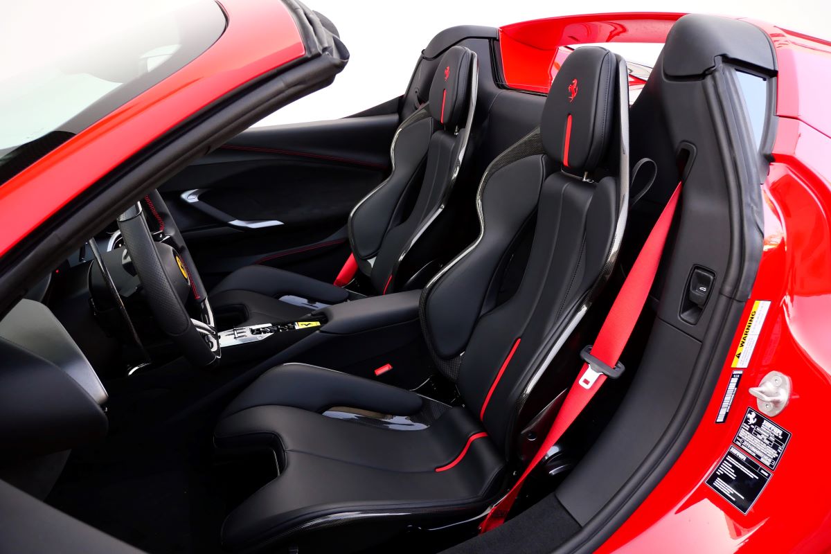 Looking down into the open 296 GTS cabin, black seats with red stripes and red seatbelts