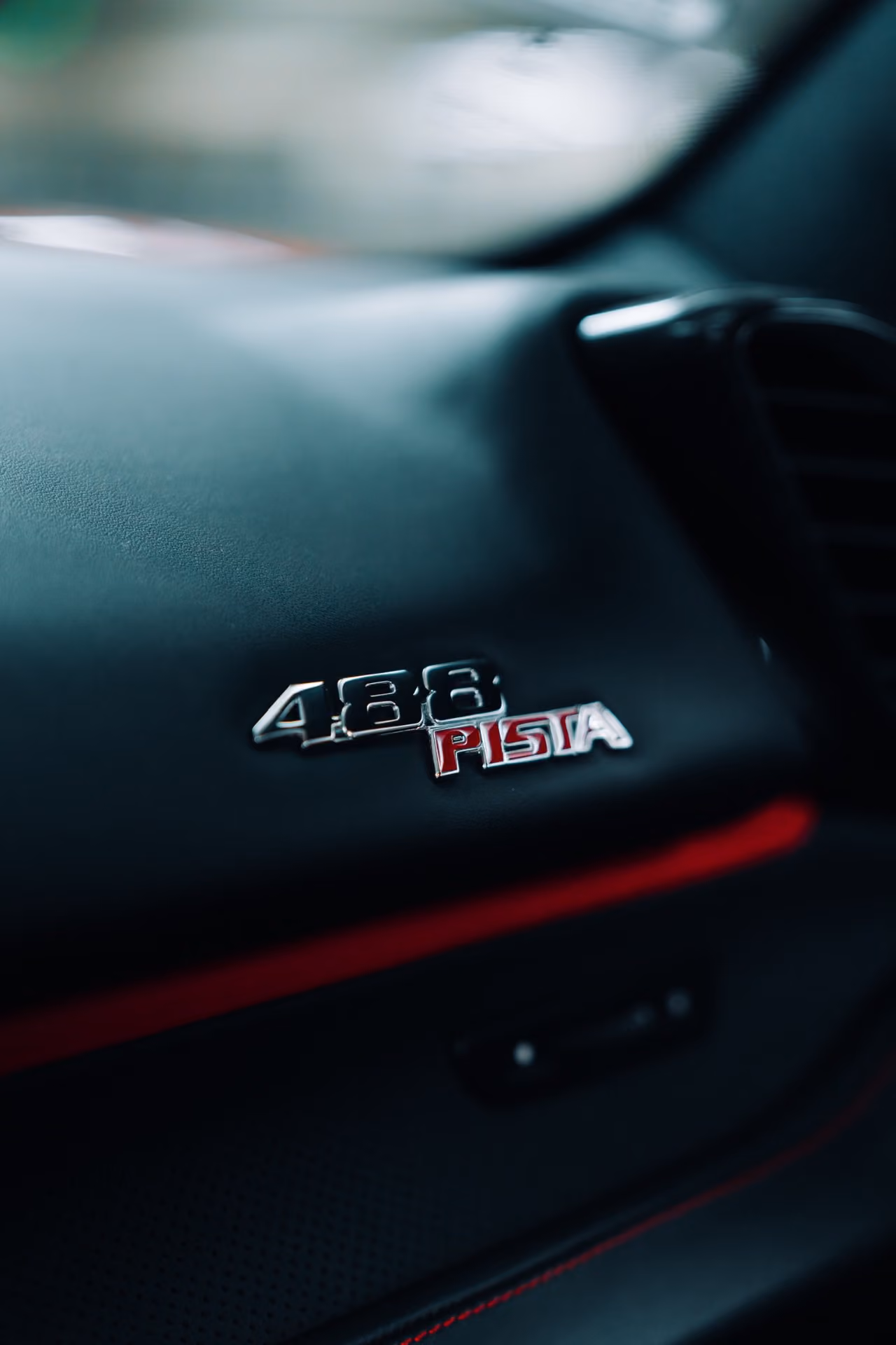 Close detail of the 488 Pista plate on the black dash with the red band running beneath it