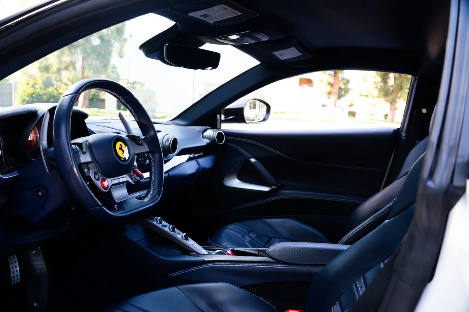 Driver's side of the 812 Superfast cabin, steering wheel with the yellow Cavallino and the black leather door
