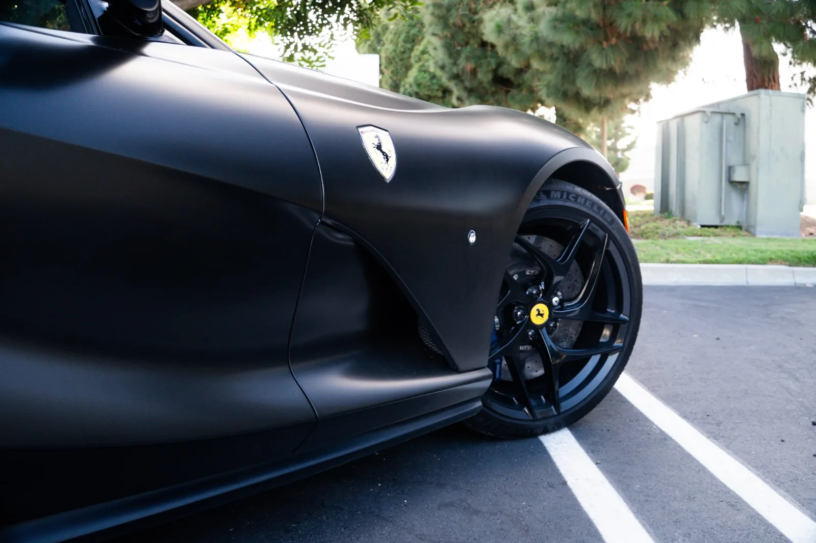 Front wing of the satin black 812 Superfast with the Scuderia shield, black wheel and blue caliper