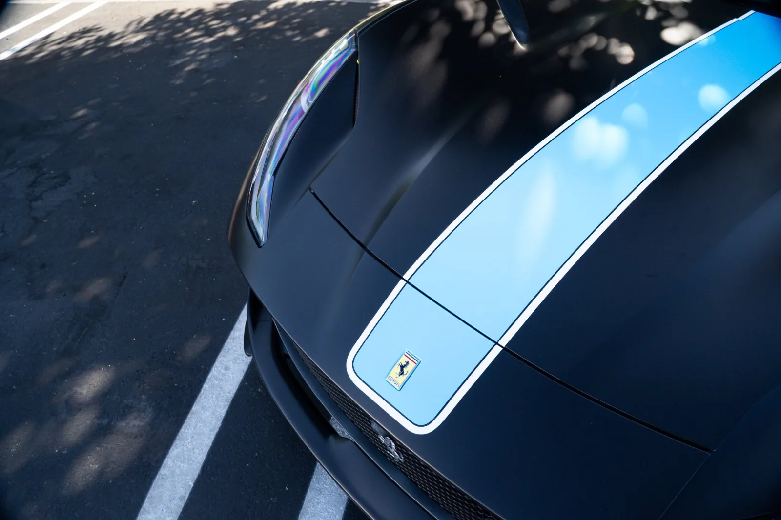 Light blue stripe running over the hood of the satin black Ferrari 812 Superfast, Cavallino badge on the nose