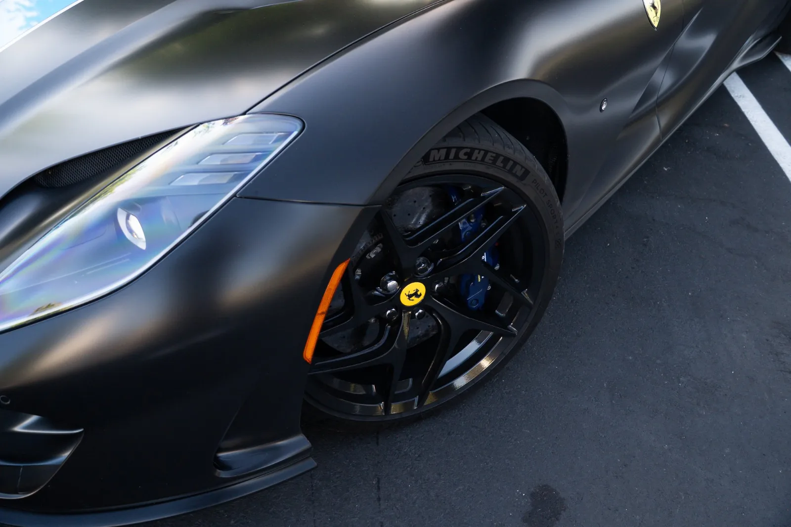 Close view of the black front wheel and blue brake caliper on the satin black 812 Superfast