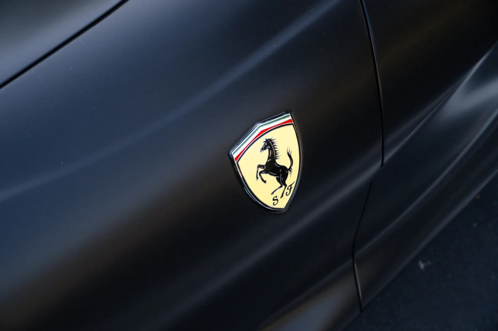 Scuderia shield on the front wing of the satin black 812 Superfast in close up