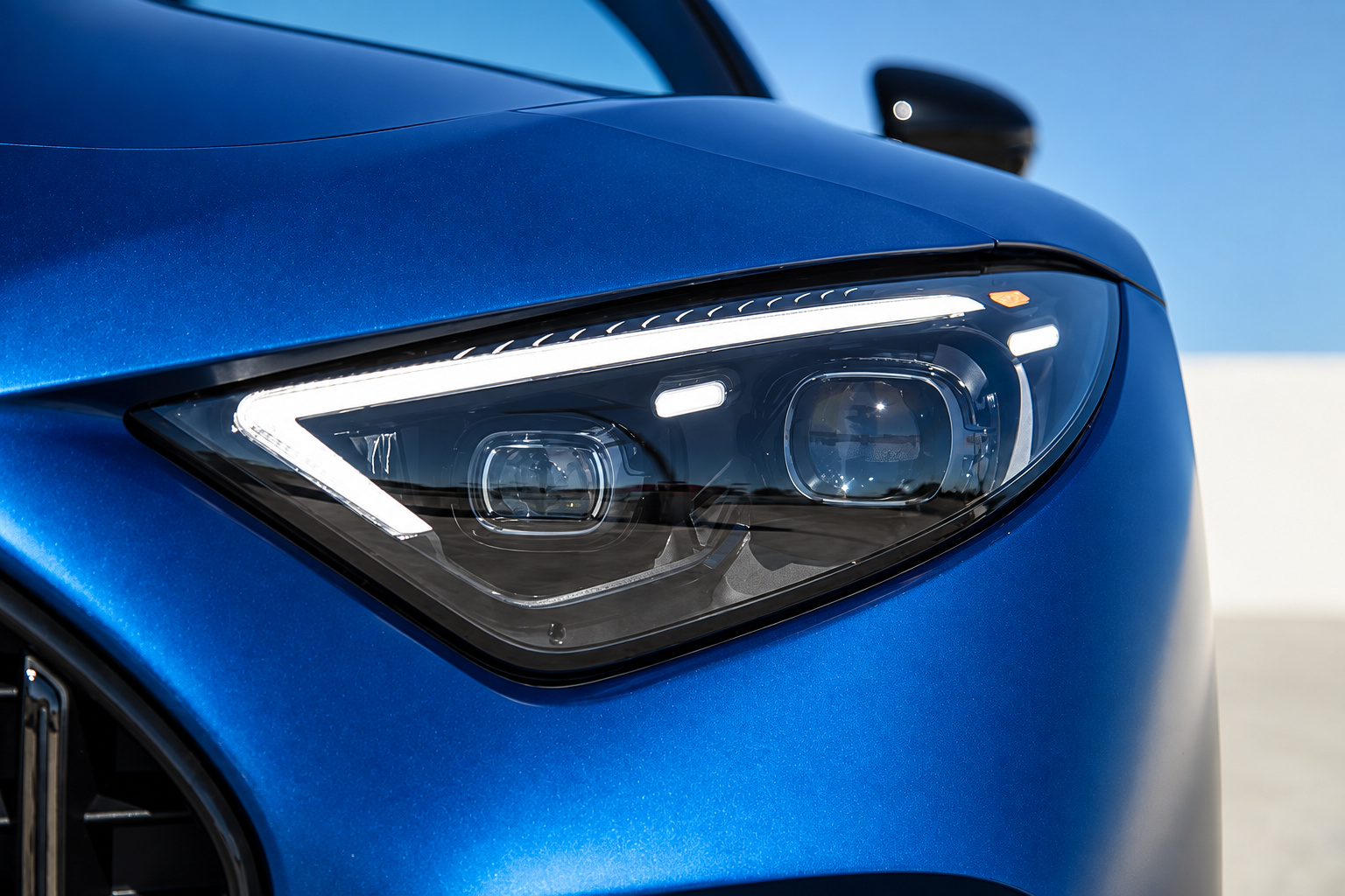Headlamp of the blue Mercedes-Benz AMG SL rental close up, LED light signature and the edge of the grille