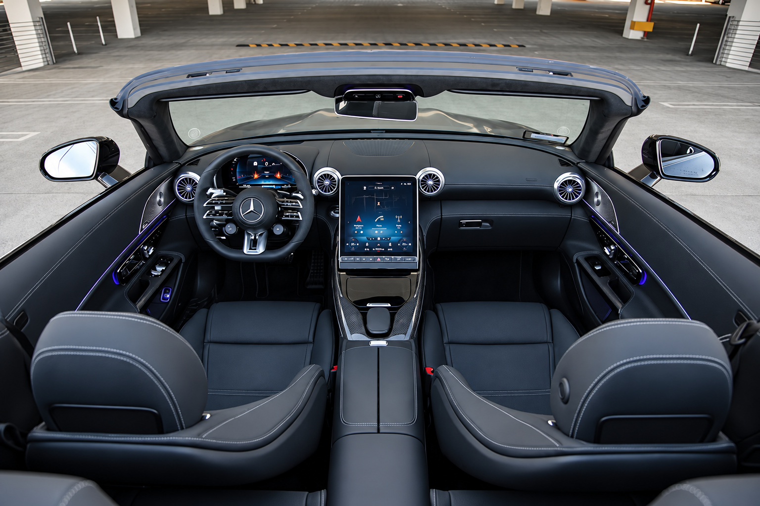 Cabin of the Mercedes-Benz AMG SL rental from above with the roof down, black seats and portrait screen