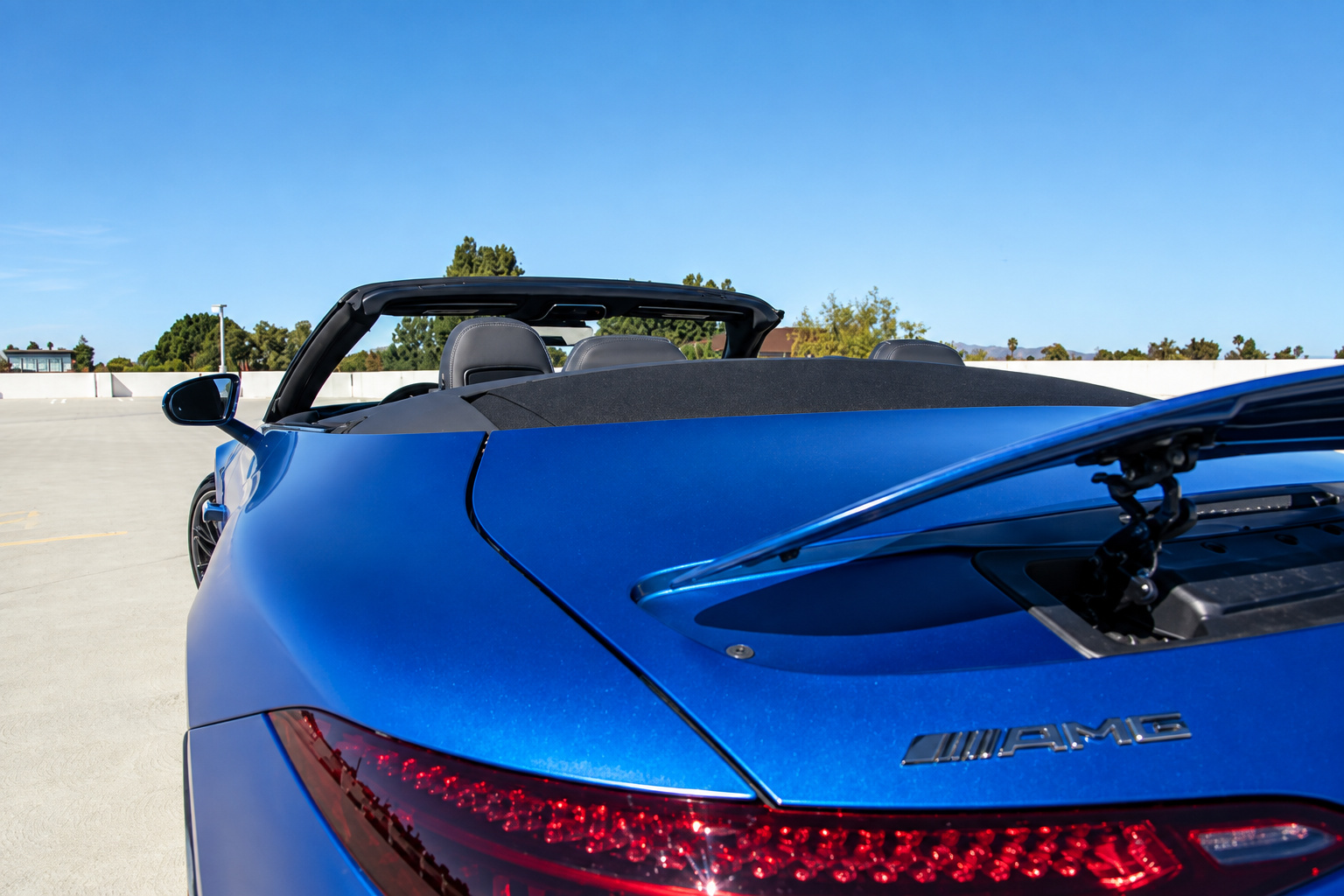 Rear corner of the blue Mercedes-Benz AMG SL rental with the roof down, tail lamp and AMG badge