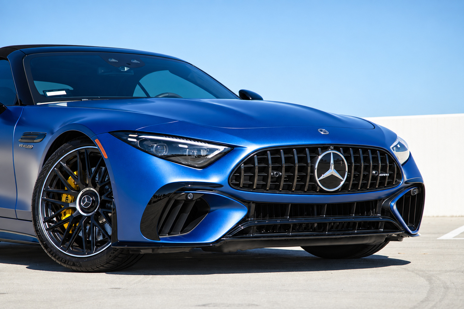Front grille of the blue Mercedes-Benz AMG SL rental close, vertical chrome bars and the star in the centre